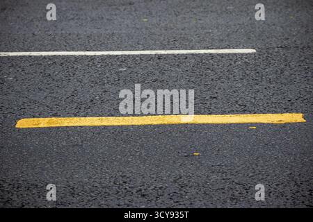 Segnaletica stradale gialla e bianca sull'asfalto Foto Stock