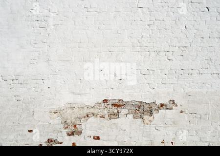 Frammento di parete in mattoni bianchi con parte di vernice danneggiata Foto Stock