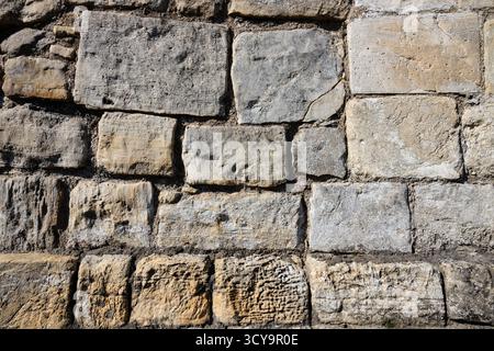 sfondo, parete, pietre rettangolari impilate per formare una struttura robusta. immagine concettuale non uniforme con pietre di colore chiaro di varie dimensioni Foto Stock