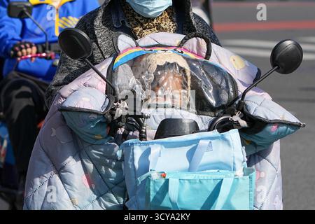 Pechino, Cina. 18 ottobre 2025. Un bambino si nasconde dal vento dietro un parabrezza su una moto a Pechino, capitale della Cina, 18 ottobre 2025. Colpita da un'aria fredda forte, Pechino è colpita da un'ondata fredda. Crediti: Ju Huanzong/Xinhua/Alamy Live News Foto Stock