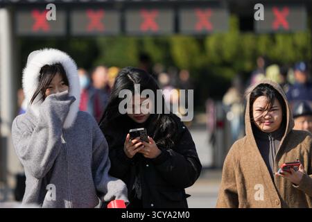 Pechino, Cina. 18 ottobre 2025. La gente cammina contro il forte vento fuori dalla porta est del Tempio del cielo a Pechino, capitale della Cina, 18 ottobre 2025. Colpita da un'aria fredda forte, Pechino è colpita da un'ondata fredda. Crediti: Ju Huanzong/Xinhua/Alamy Live News Foto Stock