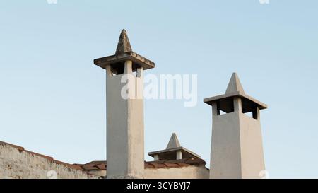 Camini e sfiati sul tetto sotto il cielo limpido sul tetto Rustic House Roof con dettagli in muratura intemprati Foto Stock