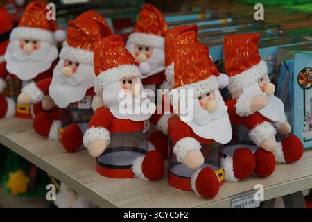 Fila di lussuosi personaggi di Babbo Natale con cappelli rossi scintillanti e barbe bianche in mostra all'Haskins Garden Centre. Foto Stock