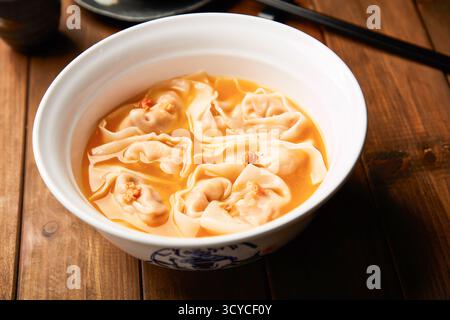 Wontons gialli Croaker nella ricca zuppa dorata nella ciotola vista laterale del piatto tradizionale cinese Foto Stock
