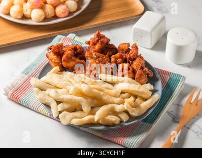 Coscia di pollo fritta, grissini croccanti, palle dolci e acide e patate servite nel piatto con forchetta isolata sul tovagliolo vista laterale del cibo di taiwan Foto Stock