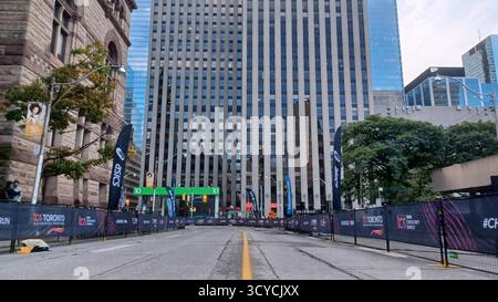 Toronto, ON, Canada - 18 ottobre 2025: Una strada vuota del centro con barriere da corsa si trova di fronte a un'alta torre di uffici prima di una maratona. Foto Stock