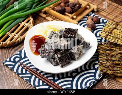 Cubo di piatto di riso con sangue di anatra con cipolla primaverile, cucchiaio e bacchette servito in piatto isolato su tovagliolo vista laterale sul tavolo cibo taiwan Foto Stock