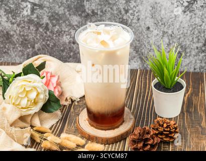 Tè nero al latte fresco freddo con cubetti di ghiaccio servito in vetro usa e getta, con vista laterale della bevanda taiwanese Foto Stock