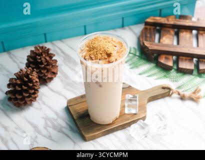 Tè al latte di germe ghiacciato con cubetti di ghiaccio in alto bicchiere servito su una tavola di legno con vista laterale della bevanda fredda di taiwan Foto Stock
