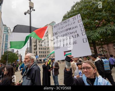 Manchester, Regno Unito. 18 ottobre 2025. Un manifestante tiene un cartello "non ancora finito" durante la marcia pro-Palestina. Nonostante il cessate il fuoco nel conflitto le proteste continuarono a Manchester. Centinaia di manifestanti si sono riuniti nei giardini di Piccadilly prima di marciare attraverso il centro della città. Più di venti manifestanti, molti con telecamere per vlogging e live streaming, hanno camminato di fronte alla protesta gridando pro Israele e slogan anti palestinesi. Credito: SOPA Images Limited/Alamy Live News Foto Stock