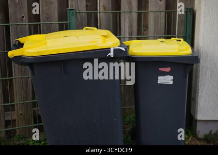 Contenitori di riciclaggio con coperchio giallo all'esterno, contenitori per la separazione dei rifiuti per plastica e imballaggio, sostenibilità ambientale e gestione del riciclaggio in re Foto Stock