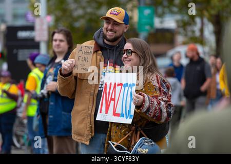 Seattle, Washington, Stati Uniti. 18 ottobre 2025. Gli spettatori tengono una varietà di segni fantasiosi durante la protesta e la marcia dei "No Kings". Si stima che 90.000 persone abbiano partecipato alla protesta di massa come parte di una giornata nazionale di azione pacifica organizzata dalla coalizione No Kings in risposta alle presunte azioni autoritarie e alla corruzione dell'amministrazione Trump. Crediti: Paul Christian Gordon/Alamy Live News Foto Stock