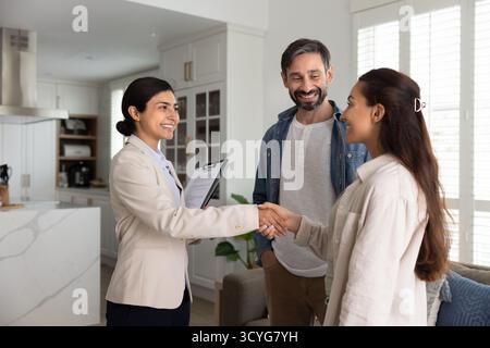 Felice coppia di famiglia stringe la mano a una donna broker immobiliare Foto Stock