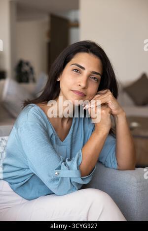 Bella donna latina positiva e premurosa che si appoggia la testa sulle mani Foto Stock