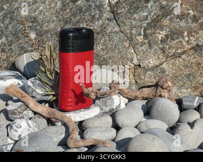 Vaso di bellezza rosso in plastica sullo sfondo di elementi naturali. Cosmetici e cura del viso e dei capelli. Modello per la progettazione. Prodotti ecocompatibili Foto Stock