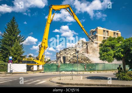 Incredibile demolizione di una vecchia casa in rovina nel centro della città utilizzando cesoie idrauliche da costruzione Foto Stock