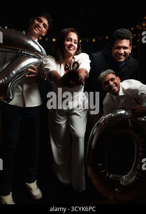 giovane donna che festeggia il suo 40esimo compleanno con la sua famiglia, sono vestite in bianco e nero e hanno una torta in mano Foto Stock