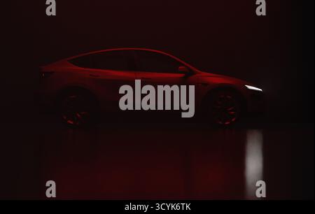 Rendering 3D di una moderna auto elettrica di colore grigio, vista completa lato destro sotto la luce rossa, sfondo nero. Foto Stock