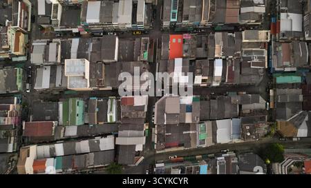 Uno scatto aereo diretto dall'alto (dall'alto verso il basso) che mostra il modello denso e irregolare dei tradizionali bassi tetti degli edifici in un quartiere di Bangkok. Foto Stock