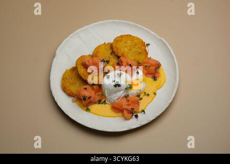 Deliziati con frittelle croccanti di patate splendidamente condite con uova in camicia e salmone affumicato saporito Foto Stock