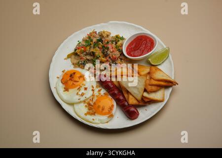 Delizioso piatto da colazione con uova strapazzate, patate croccanti e salsiccia salata Foto Stock