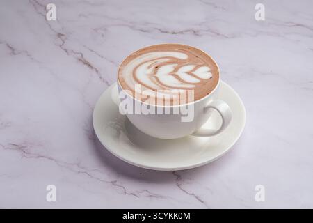 Goditi una deliziosa tazza di cioccolata calda adornata da un design in schiuma elegante e intricato Foto Stock