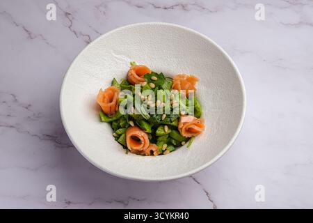 Una deliziosa insalata verde fresca con salmone succulento e fiori commestibili splendidamente disposti Foto Stock