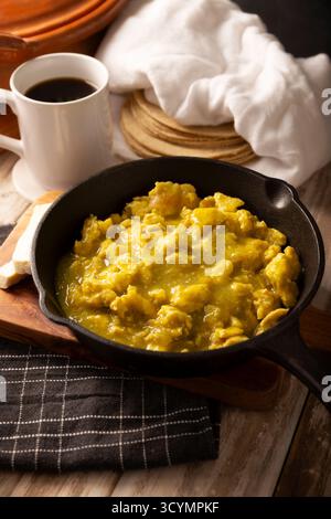 Uova strapazzate in salsa verde. Una tipica colazione messicana a base di uova strapazzate bagnate da salsa verde piccante, di solito accompagnate da fagioli e caffettiera. Foto Stock