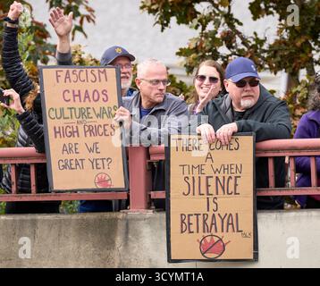 La gente tiene dei cartelli ad una manifestazione dei No Kings a Eugene, Oregon, il 18 ottobre 2025. Foto Stock