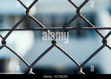 Primo piano di una recinzione arrugginita con maglie a catena con sfondo sfocato Foto Stock