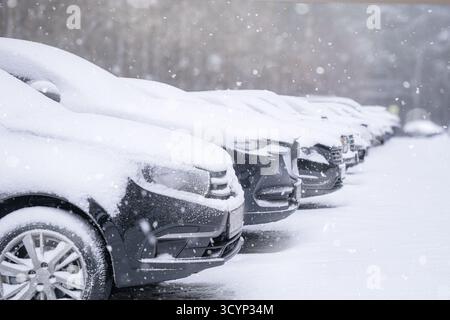 Nevicate, auto coperte di neve in fila nel parcheggio. La scena delle SnowCovered Cars è situata in una splendida atmosfera invernale nel paese delle meraviglie Foto Stock