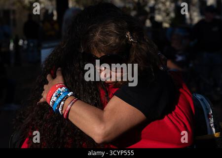 Washington, Stati Uniti. 18 ottobre 2025. Una donna che partecipa alla manifestazione Lost Voices of Fentanyl abbraccia un manifestante dei No Kings a Lafayette Park, sabato 18 ottobre 2025, a Washington. Lost Voices of Fentanyl è un gruppo di famiglie che hanno perso i propri cari a causa del fentanyl e che sostengono le politiche di immigrazione del presidente Trump come soluzione ai problemi con la droga. Credito: SOPA Images Limited/Alamy Live News Foto Stock