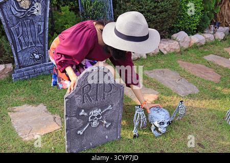 Donna che decora il cortile con teschio replica per le vacanze di Halloween Foto Stock
