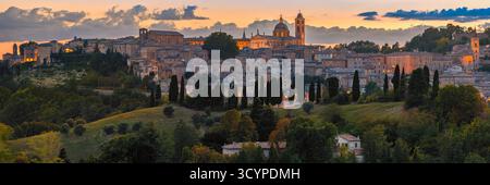 Una vista panoramica ultra-ampia (XPan) di Urbino, Marche, Italia, catturata dopo il tramonto. Lo skyline rinascimentale brilla di calde luci serali e stretchin Foto Stock