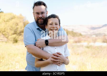 Padre e figlio abbracciano e sorridono Foto Stock