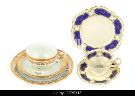 Due eleganti set da tè in porcellana d'epoca, caratterizzati da intricate finiture in oro e motivi blu cobalto, sono isolati professionalmente su uno sfondo bianco pulito Foto Stock