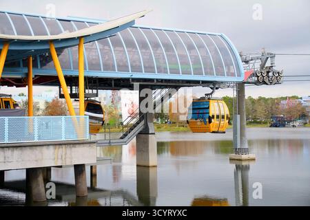Primo piano delle gondole Disney Skyliner con partenza dalla stazione Art of Animation Resort sopra un lago riflettente di Orlando Foto Stock