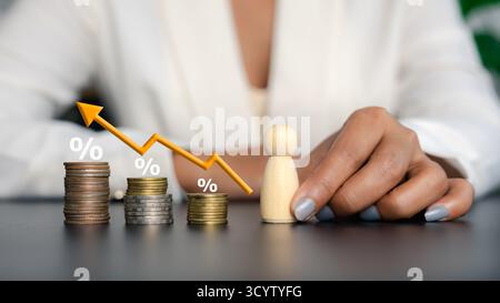 Pila di monete con segni percentuali e grafici con linee a freccia che mostrano l'aumento e il calo dei tassi di interesse e dell'economia, il concetto di inflazione, la crescita degli investimenti Foto Stock