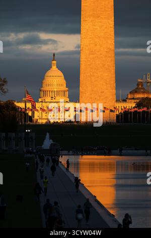 Il Campidoglio DEGLI STATI UNITI e il Washington Monument National Mall Washington DC / WASHINGTON DC - il Monumento a Washington e il Campidoglio degli Stati Uniti sono illuminati dalla luce dorata del tramonto sul National Mall. Il monumento a Washington, un obelisco in onore di George Washington, è alto 169,29 metri (555 piedi e 5 pollici). Il Campidoglio degli Stati Uniti, sormontato dalla sua iconica cupola, è la sede del Congresso degli Stati Uniti. Questi importanti punti di riferimento si trovano sul National Mall, un importante parco nazionale della città, con la Rainbow Pool del Memoriale della seconda Guerra Mondiale visibile in primo piano. Foto Stock