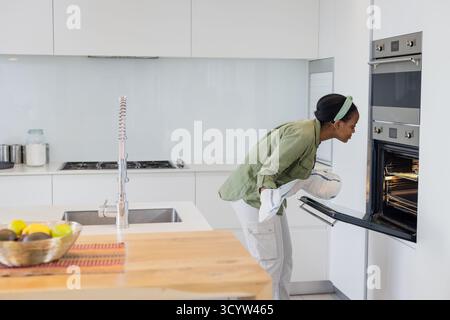 ripiano isolano in legno con cesto di frutta e rubinetto a molla accanto al piano cottura a gas in cucina Foto Stock
