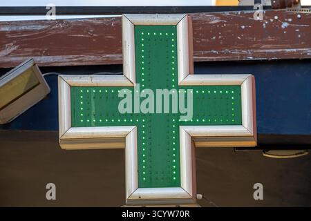 Insegna verde brillante della farmacia che illumina il cartello verde della farmacia appeso su una facciata di un edificio urbano Foto Stock