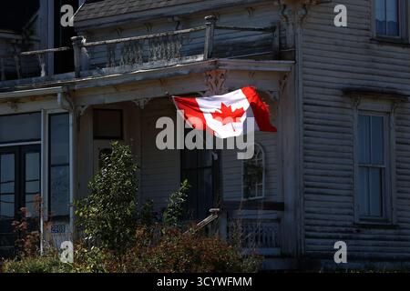 Bandiera canadese sulla vecchia casa di legno alla luce del giorno Foto Stock