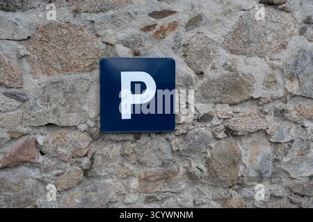 Segnale di parcheggio blu con il simbolo "p" sul muro di pietra Foto Stock