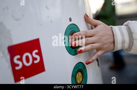 Berlino, Germania. 20 ottobre 2025. Una giovane donna preme il pulsante su una colonna chiamata di emergenza durante una dimostrazione del lavoro di sicurezza del Berliner Verkehrsbetriebe (BVG) alla stazione 'Kottbusser Tor'. Crediti: Britta Pedersen/dpa/Alamy Live News Foto Stock