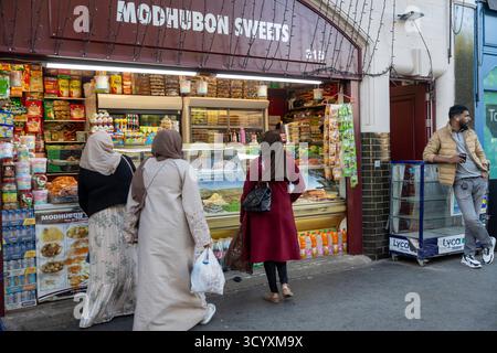 Londra, Regno Unito, 2 maggio 2025. Clienti, tra cui tre donne in hijab e un uomo appoggiato a uno stand, fai acquisti presso modhubon Sweets, un negozio di dolci bengalesi a. Foto Stock
