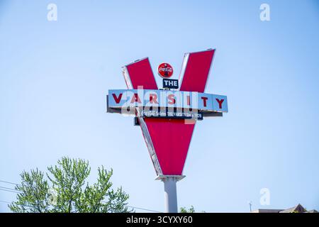 L'iconico simbolo rosso della "V" per The Varsity, uno storico ristorante drive-in fondato nel 1928, si erge su un cielo azzurro limpido vicino ad alcuni alberi verdi Foto Stock