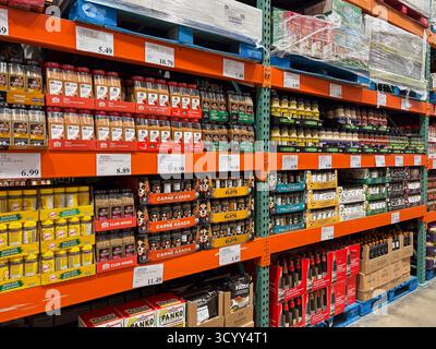 Interno del magazzino Costco con ripiani in metallo arancione completamente riforniti di alimenti sfusi, condimenti, salse e bevande. I prezzi sono visibili, DIPI Foto Stock