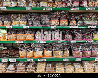Frutta secca e frutta secca confezionate esposte su più ripiani in un supermercato canadese. Varietà di mandorle, noci, noci miste, arachidi e fagioli secchi Foto Stock