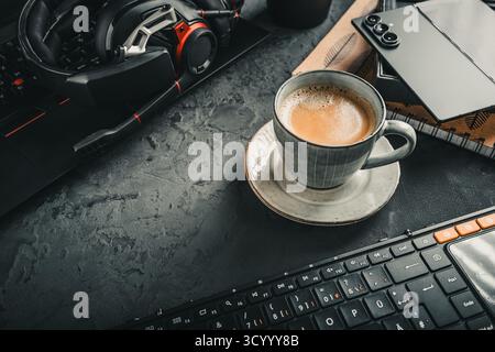 Scrivania da ufficio con computer portatile, tazza di caffè e provviste. Foto Stock
