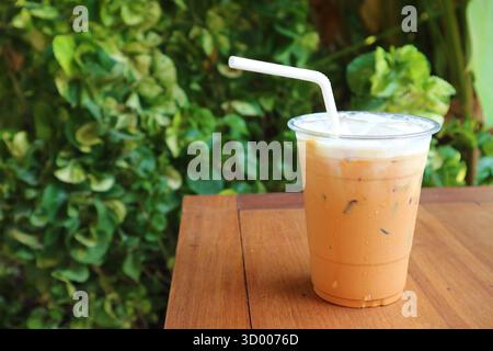 Una tazza di gustoso tè freddo tailandese sul tavolo da giardino Foto Stock